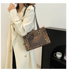 Close-up of leopard print tote bag with brown pocket worn over a beige trench coat