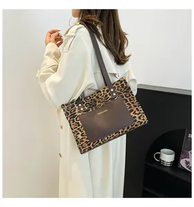 Detail of leopard print canvas tote bag featuring a brown front pocket and shoulder strap