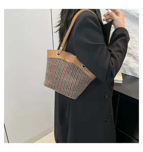 Détail d'un sac à bandoulière pied-de-poule avec bandoulière en cuir marron