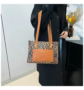 Detailed view of the leopard print tote bag with brown leather pocket and long straps