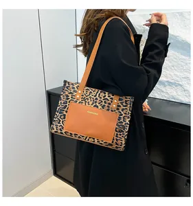 Leopard print tote bag with brown leather pocket detail shown on model's shoulder
