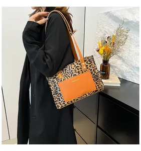 Detail of trendy leopard print tote bag featuring a brown leather pocket and strap