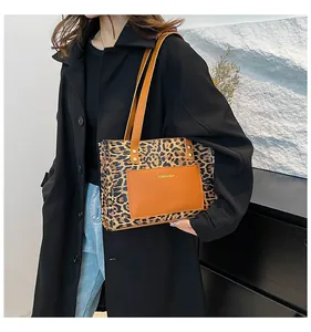 Close-up of leopard print tote bag with brown leather straps and front pocket detail