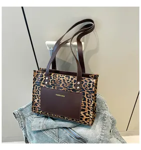 Detail of leopard print tote bag with brown leather pocket and gold rivet accents