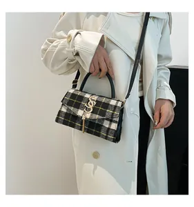 Primer plano detallado del bolso bandolera de tweed blanco y negro con adornos dorados y borla