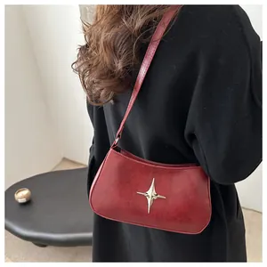 Détail du sac croissant bordeaux avec étoile métallique montré en porté épaule chic