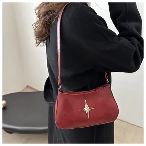 Détail du sac à bandoulière croissant bordeaux avec texture vintage et boucle étoile argentée