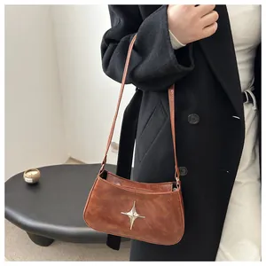 Détail montrant la texture du similicuir marron et l'ornement étoile argenté du sac bandoulière