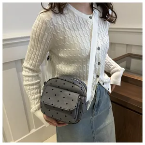 Detail of grey polka dot crossbody bag with white wide strap and quilted fabric texture