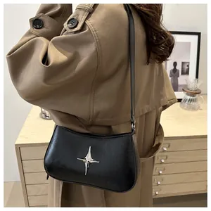 Détail du sac demi-lune noir en cuir brillant porté avec un trench-coat classique