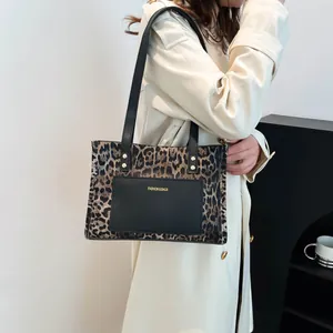 Chic leopard print tote bag with black pocket carried by a model in a trench coat