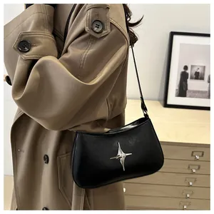 Détail du sac demi-lune noir en cuir mat orné d'un pendentif en métal en forme d'étoile
