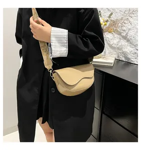 Detail of beige saddle bag with decorative wide jacquard strap and gold hardware