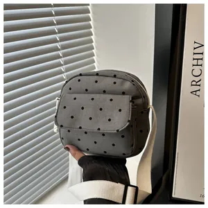 Close-up of grey polka dot canvas crossbody bag with front flap pocket and white strap