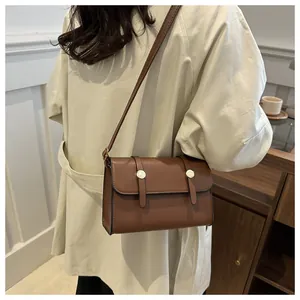 Detail van vintage bruine vierkante crossbodytas met gouden metalen gesp op jas