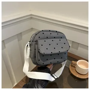 Macro detail of grey polka dot fabric crossbody bag with white woven strap