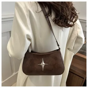 Détail du sac croissant en daim marron foncé avec ornement étoile argentée porté par modèle