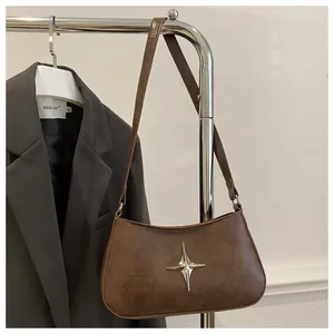 Détail d'un sac demi-lune marron avec ornement étoile à quatre branches en argent poli