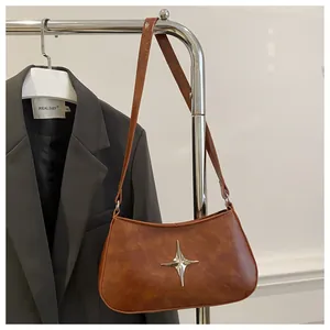 Vue détaillée d'un sac d'épaule croissant marron rétro avec ornement d'étoile en métal