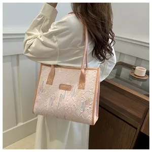 Detail of pink canvas tote bag showing fashion embroidery and side carrying view on shoulder