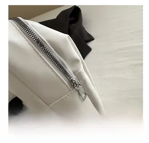 Detail view of smooth silver metal zipper on premium white PU leather crossbody bag