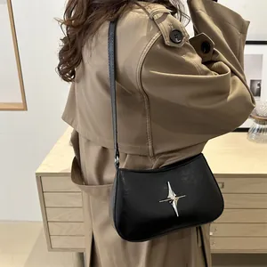 Sac hobo noir minimaliste avec boucle étoile argentée porté par un mannequin