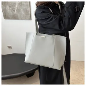 Détail du sac cabas minimaliste gris en cuir avec barre métallique et bandoulière sur mannequin