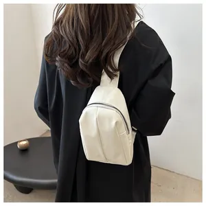 Rear view of model wearing a creamy white leather chest bag with silver metal zippers