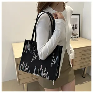 Detail of a black canvas tote bag with colorful wave embroidery worn on a shoulder