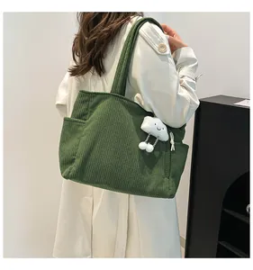 Macro detail of dark green corduroy tote bag featuring side pocket and plush cloud charm