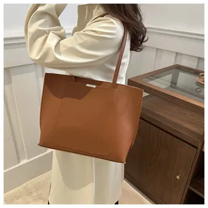 Détail d'un sac cabas en cuir synthétique marron avec boucle argentée et fines lanières