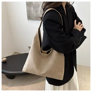 Dettaglio della borsa tote beige in morbido camoscio indossata da una modella in stile minimal