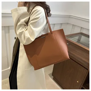 Détail du sac cabas marron montrant la poche avant et le décor en barre métallique argentée