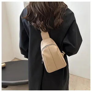Rear view of a beige crescent-shaped crossbody chest bag on a model with wide strap