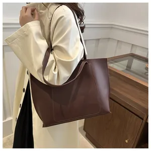 Détail d'un grand sac cabas marron foncé avec poche latérale et bandoulière sur modèle