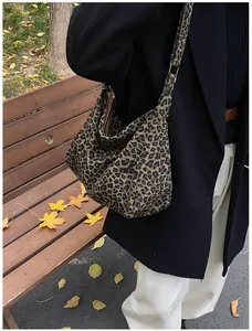 Détail du sac cabas imprimé léopard avec boucle métallique dans un décor d'automne