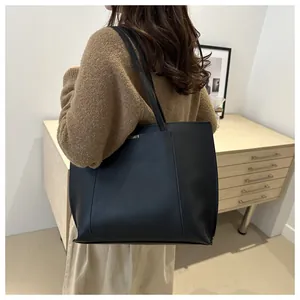 Détail d'un grand sac cabas noir avec texture en cuir mat et détail en métal argenté