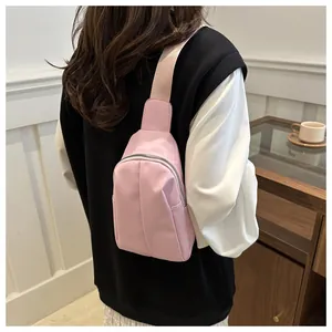 Detail view of pink crossbody bag with pleated texture and wide strap on model back