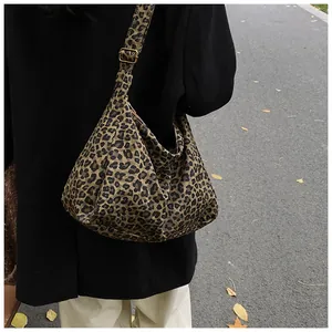 Vue de rue d'un sac hobo à imprimé léopard avec bandoulière réglable sur un manteau