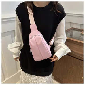 Detailed view of a pink fabric crossbody chest bag worn by a model in a natural setting