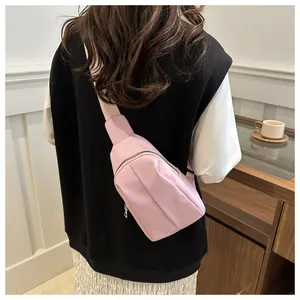 Detailed back view of a pink nylon crossbody chest bag with adjustable wide fabric strap