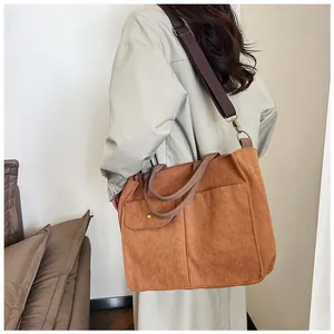 Gros plan sur le sac fourre-tout en velours côtelé marron et sa bandoulière réglable