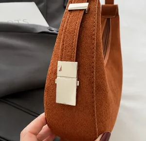 Detailed close-up of brown suede leather texture and silver buckle on the crescent bag