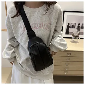 Detail of black pleated crossbody bag with metal zipper and wide nylon shoulder strap