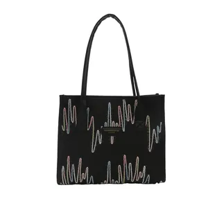 Minimalist black canvas tote bag featuring colorful wave embroidery and leather straps