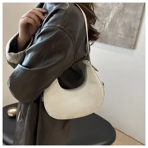 Detailed side view of a white crescent hobo bag made of matte leather on a model's shoulder