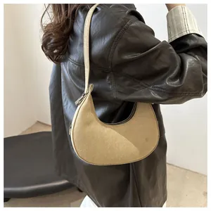 Close-up of light brown suede crescent underarm bag with zipper and stitching details