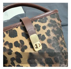 Close-up of golden metal twist lock and brown leather strap on leopard print bucket bag