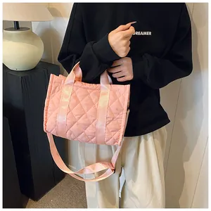 Detail of pink quilted tote bag showing diamond stitching and wide woven strap handle