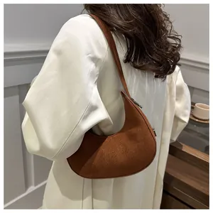 Detail of a brown suede crescent underarm bag with smooth zipper and slim strap